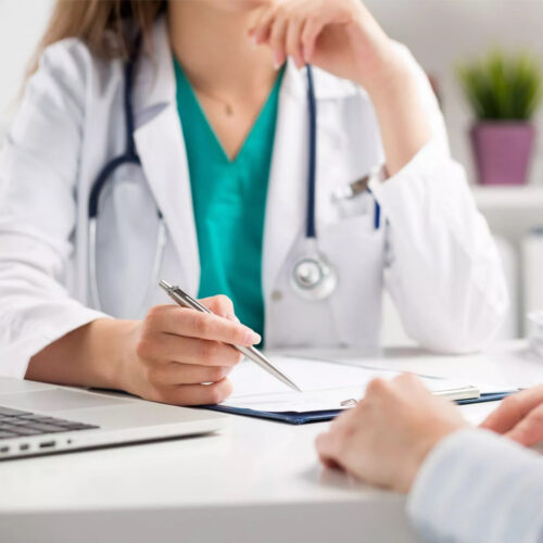 γιατρός με άσπρη ποδιά κρατάει σημειώσεις και συμβουλεύει ασθενή